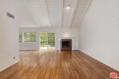 a view of empty room with wooden floor and fireplace