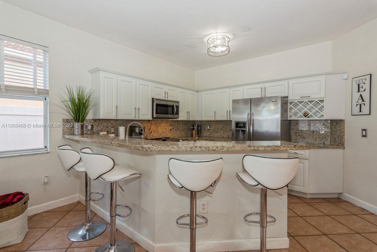 2240 Northeast 37th Terrace Homestead, FL 33033 - Photo 6 of 18 a kitchen with stainless steel appliances granite countertop a white cabinets and stove top oven
