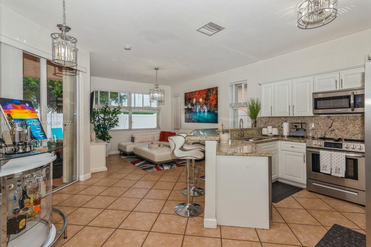 2240 Northeast 37th Terrace Homestead, FL 33033 - Photo 10 of 18 a open kitchen with stainless steel appliances granite countertop a stove top oven a sink dishwasher a dining table and chairs with wooden floor