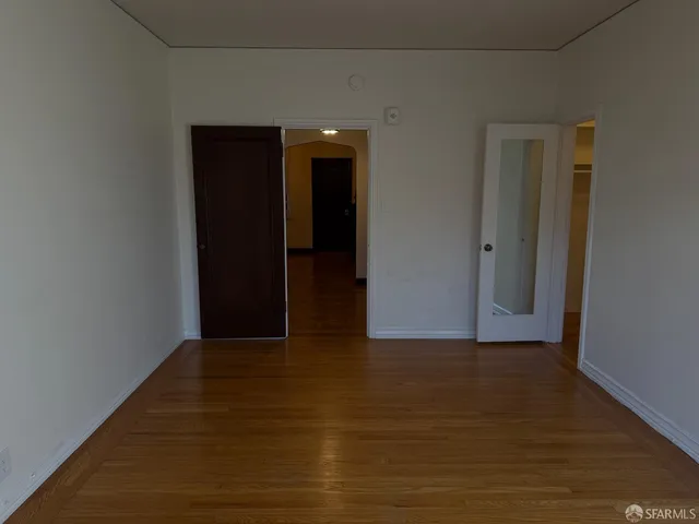 a view of an empty room with wooden floor and closet