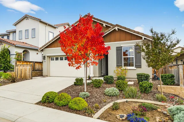 a view of a white house next to a yard with potted plants