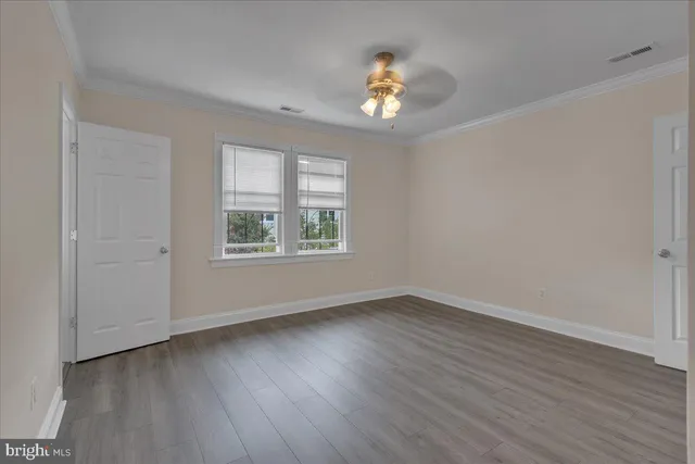 a view of an empty room with a window and wooden floor