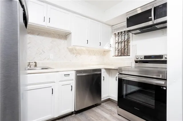 a kitchen with white cabinets and appliances