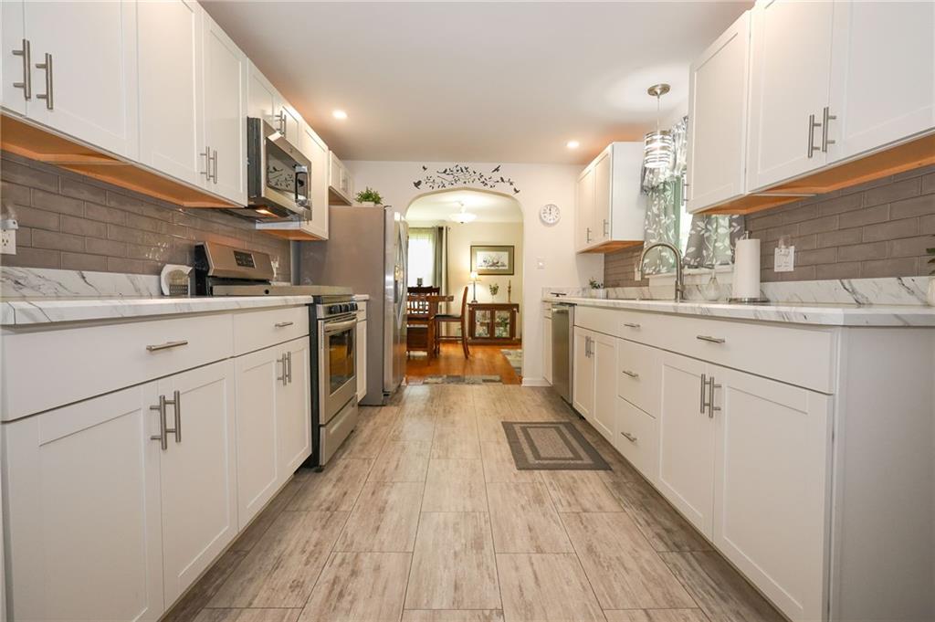 1069 North Keel Ridge Road Hermitage, PA 16148 - Photo 8 of 50 a large white kitchen with cabinets a sink dishwasher and a stove with wooden floor