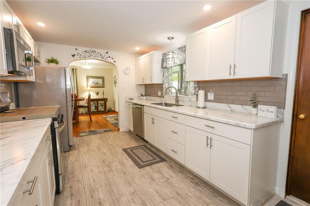 1069 North Keel Ridge Road Hermitage, PA 16148 - Photo 9 of 50 a large white kitchen with a lot of counter space and wooden floor