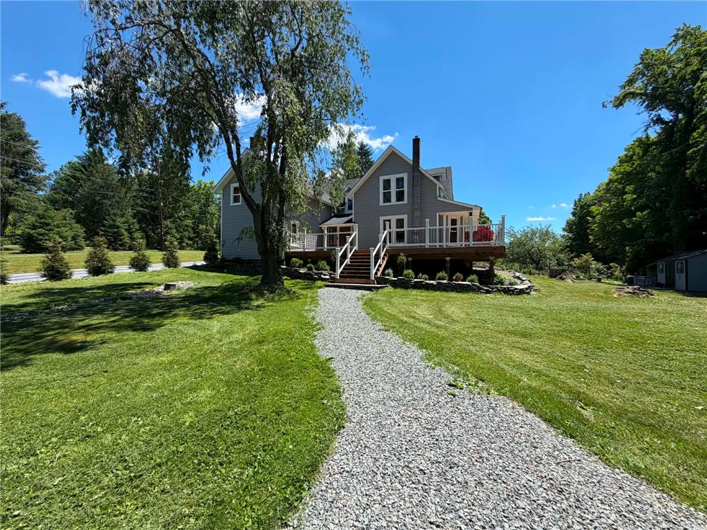 164 Sand Spring Road Cresco, PA 18326 - Photo 2 of 60 A long gravel path leads to a charming residence with a spacious wooden deck overlooking verdant grounds.
