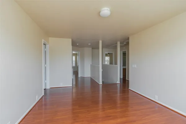 a view of an empty room with wooden floor and a window