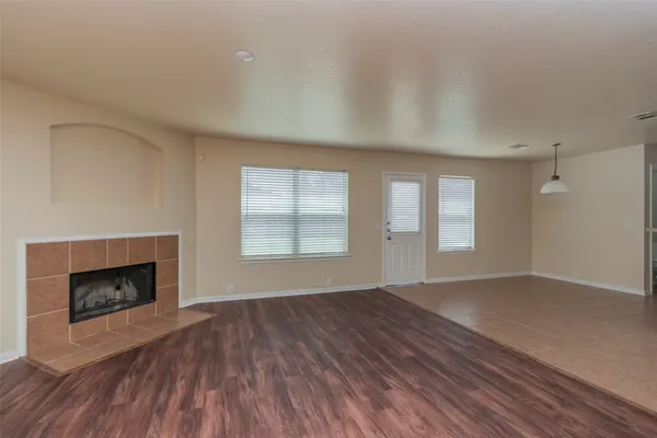 an empty room with wooden floor fireplace and windows