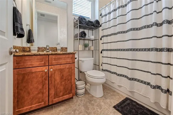 a bathroom with a granite countertop toilet sink and mirror