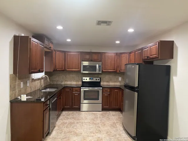 a kitchen with granite countertop stainless steel appliances and refrigerator