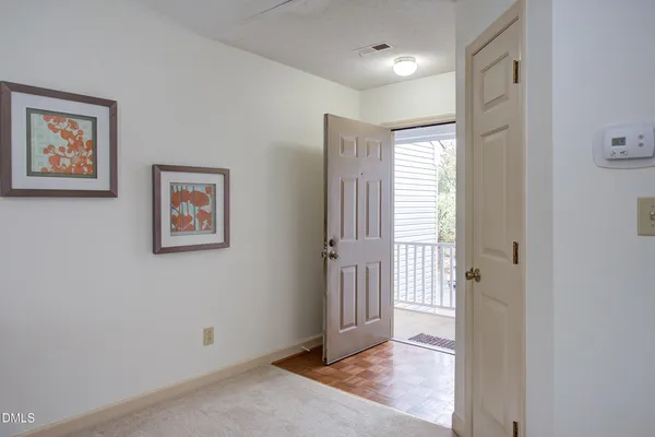 a view of a hallway with wooden floor and a bathroom