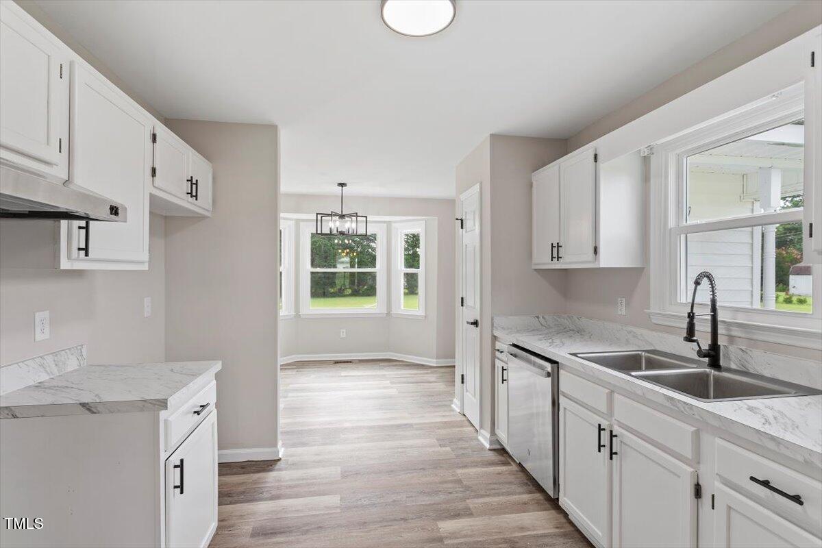 1480 White Memorial Church Road Willow Spring, NC 27592 - Photo 9 of 23 a kitchen with a sink dishwasher a stove and white cabinets with wooden floor
