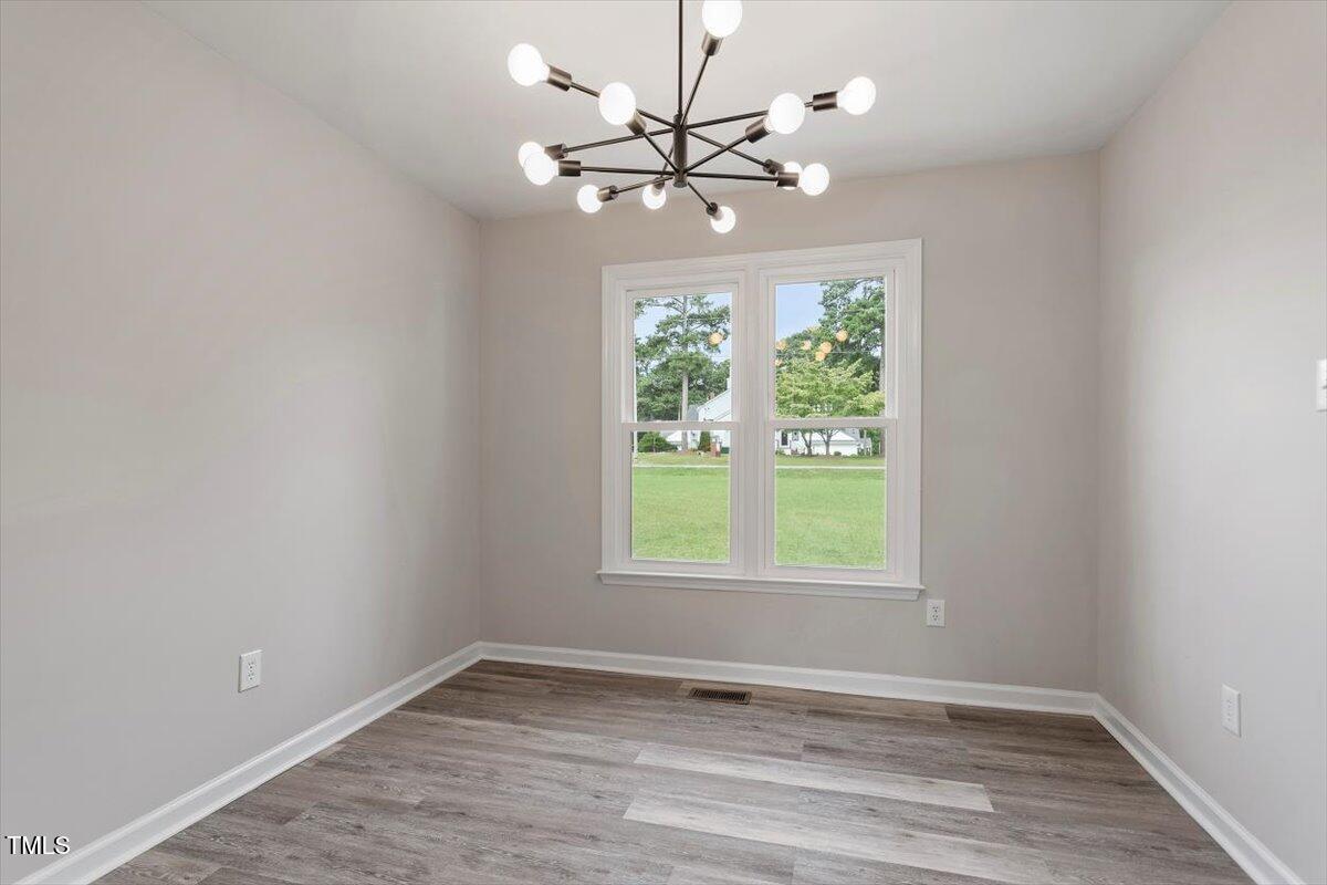 1480 White Memorial Church Road Willow Spring, NC 27592 - Photo 10 of 23 an empty room with wooden floor chandelier fan and windows