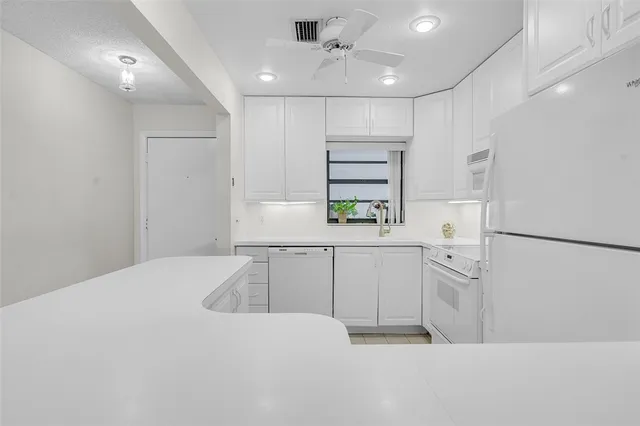 a kitchen with white cabinets and refrigerator