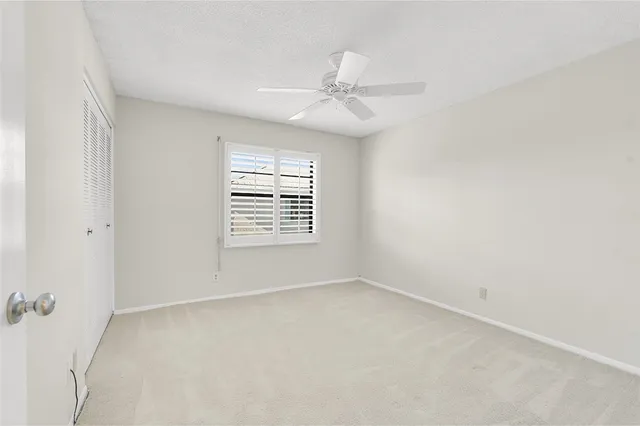 an empty room with a window and a fan
