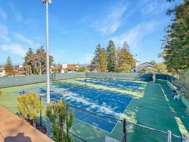 a view of a tennis ground with large trees