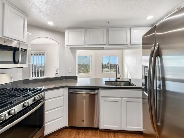 a kitchen with white cabinets and appliances