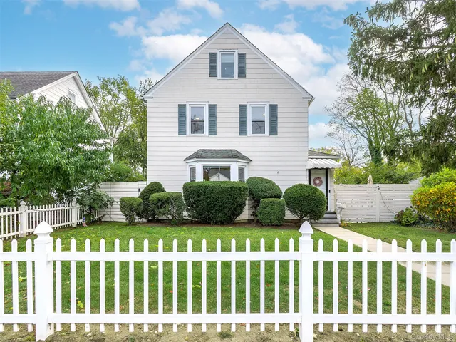 a front view of white house with a garden