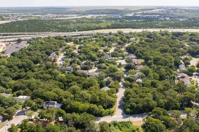 an aerial view of residential houses with outdoor space and trees