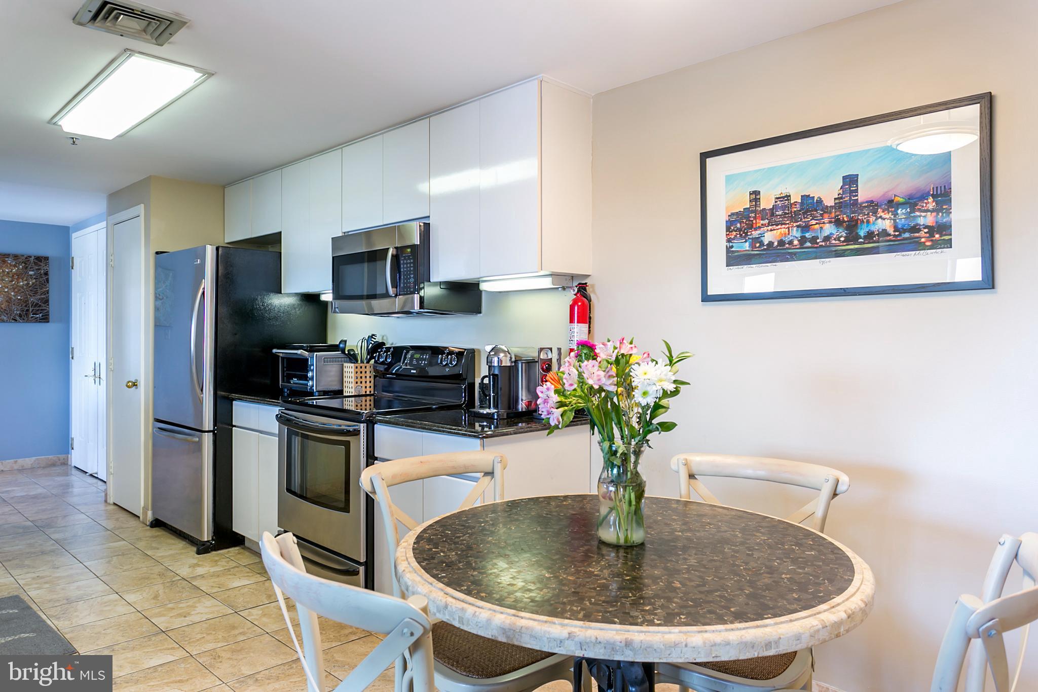 250 President Street, Unit 605 Baltimore, MD 21202 - Photo 3 of 38 a kitchen with stainless steel appliances granite countertop a refrigerator a stove a microwave and a dining table