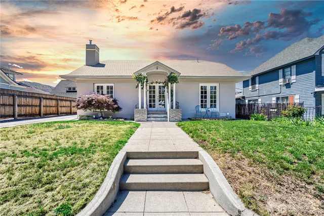 a front view of a house with a yard and potted plants