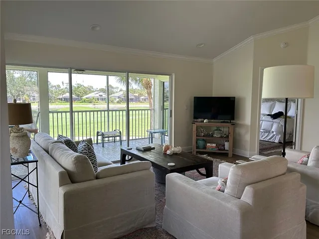 a living room with furniture a flat screen tv and a floor to ceiling window