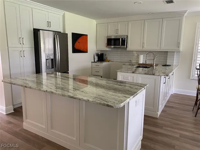 a kitchen with stainless steel appliances granite countertop a refrigerator stove microwave and sink