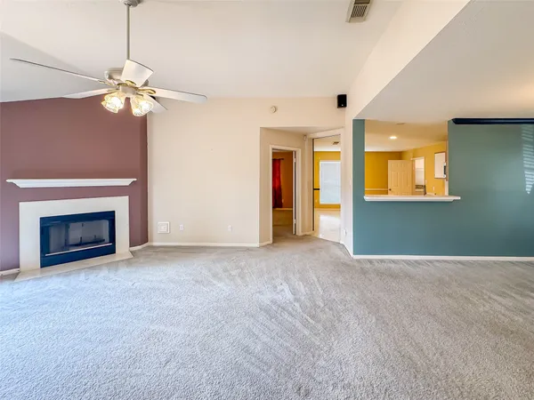 a view of an empty room with window and chandelier fan