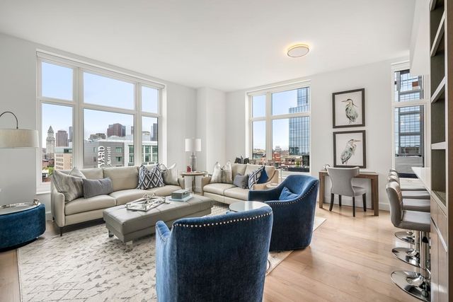 a living room with furniture potted plant floor to ceiling windows and a flat screen tv