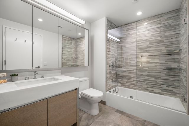 a bathroom with a bathtub shower sink vanity mirror and toilet