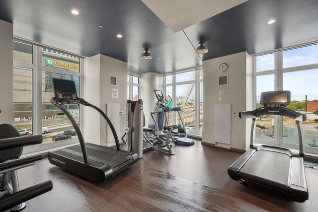 a view of a room with gym equipment and wooden floor