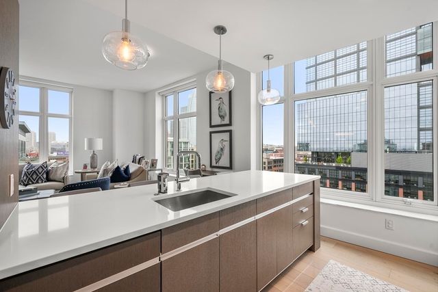 a view of a kitchen counter top space a sink wooden floor and windows