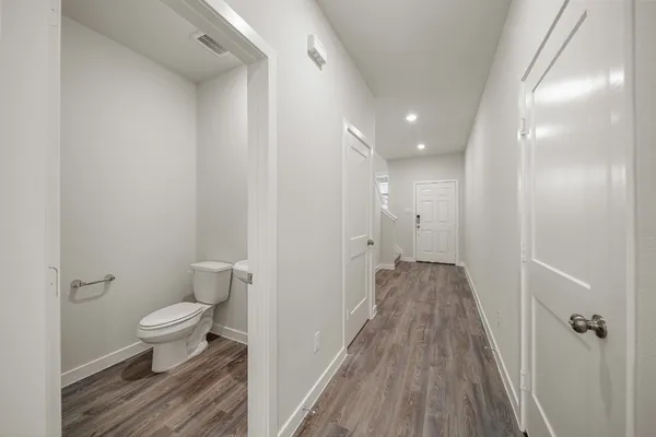 a view of a hallway with toilet and wooden floor