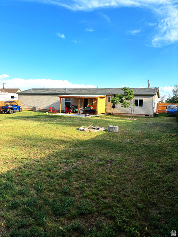 547 East 2000th Street North Vernal, UT 84078 - Photo 2 of 50 Expansive grassy yard featuring a covered patio, a fire pit, and a small tree