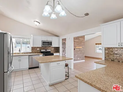 a kitchen with stainless steel appliances granite countertop a stove top oven a sink dishwasher a dining table and chairs with wooden floor