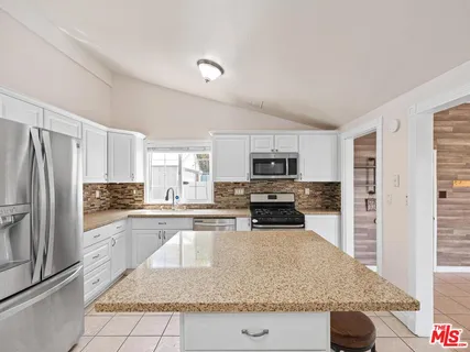a kitchen with stainless steel appliances granite countertop a refrigerator stove microwave and sink