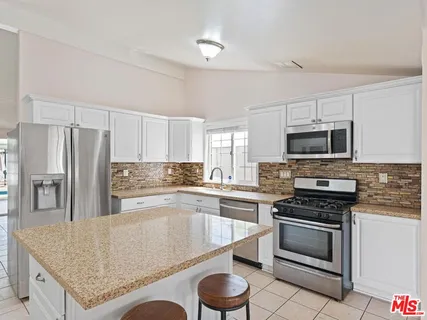 a kitchen with granite countertop a stove sink and refrigerator