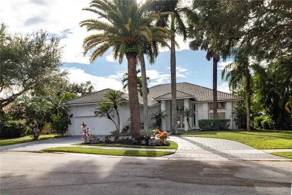 a view of a house with a yard and palm trees