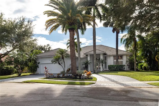 a view of a house with a yard and palm trees
