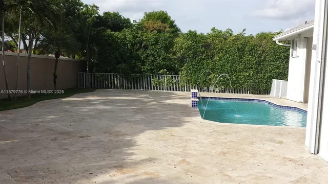 a view of a backyard with large trees and wooden fence
