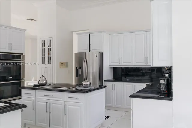 a kitchen with granite countertop a refrigerator and a stove top oven