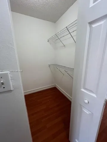 an empty room with wooden floor chandelier fan and windows