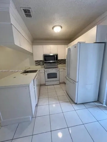 a kitchen with stainless steel appliances a stove a sink and white cabinets