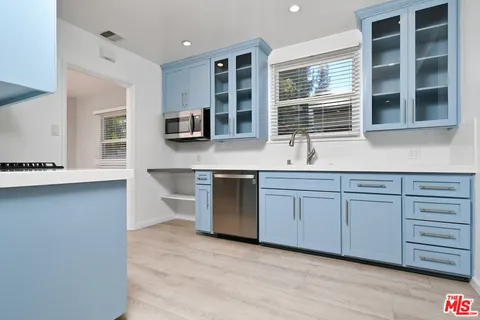 a dining hall with stainless steel appliances granite countertop a stove a sink a dining table and chairs with wooden floor