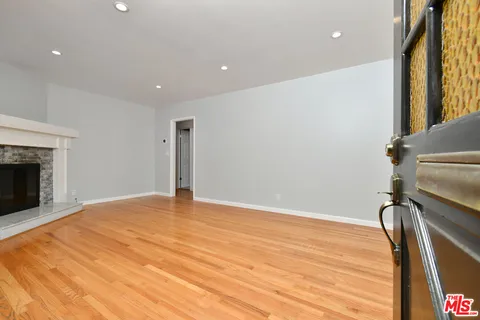 a view of an empty room with wooden floor and a fireplace