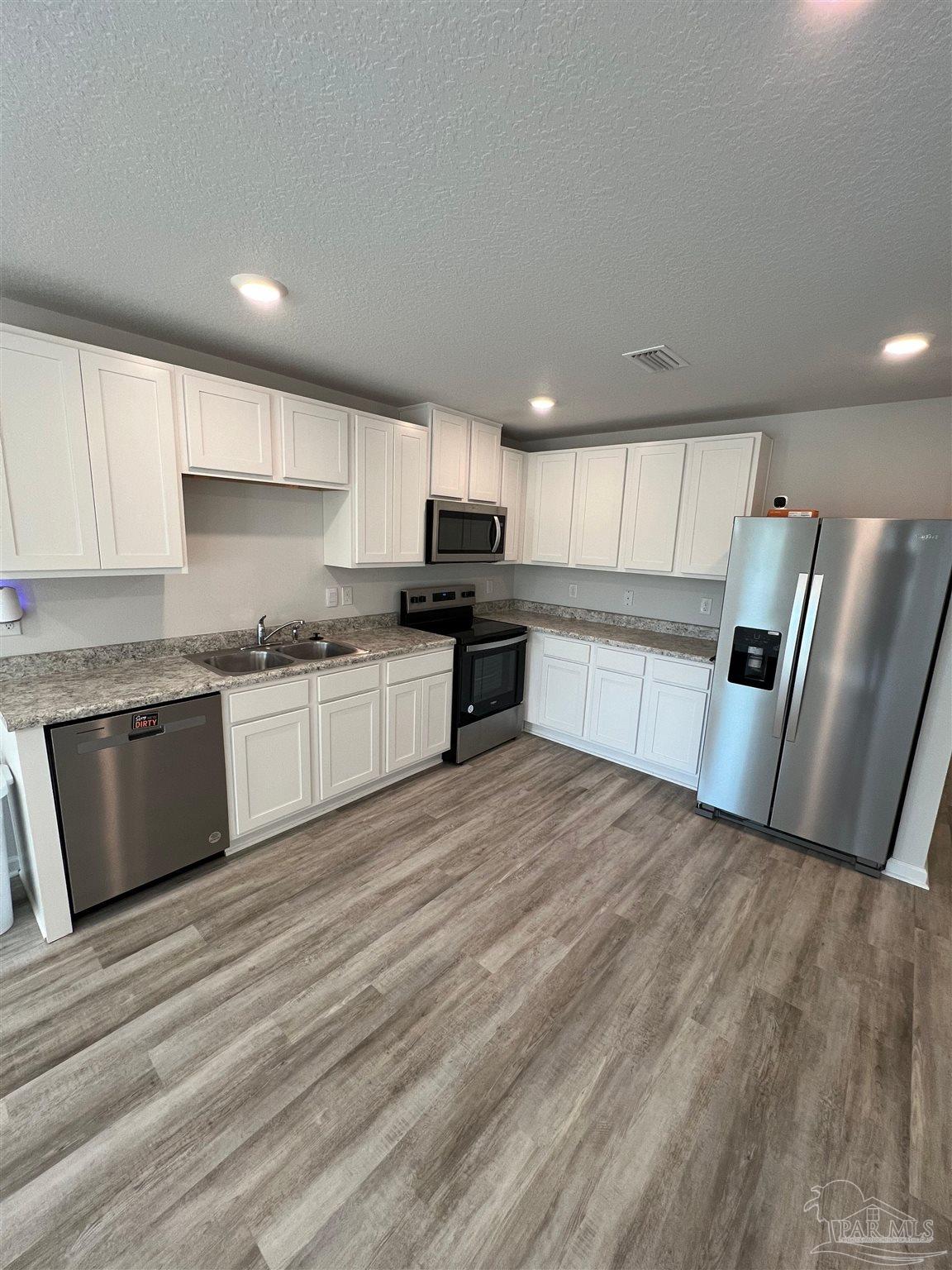 6235 June Bug Drive Milton, FL 32583 - Photo 7 of 20 a kitchen with granite countertop a refrigerator stove top oven and sink