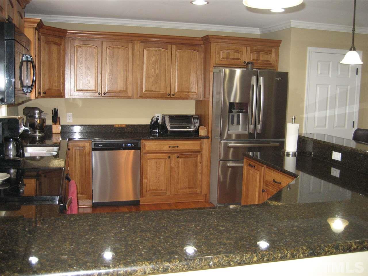 9740 South Lowell Road Bahama, NC 27503 - Photo 7 of 17 a kitchen with stainless steel appliances granite countertop a refrigerator a stove and a sink with wooden cabinets