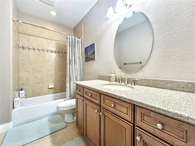 a spacious bathroom with a granite countertop sink toilet a mirror and shower