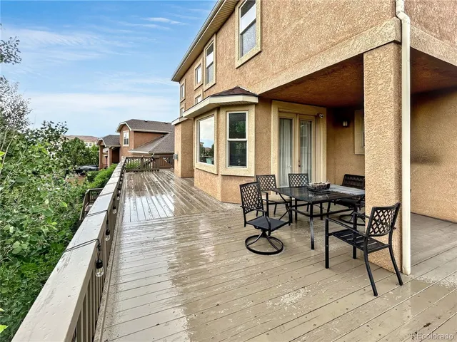 a view of a patio with table and chairs with wooden floor and fence