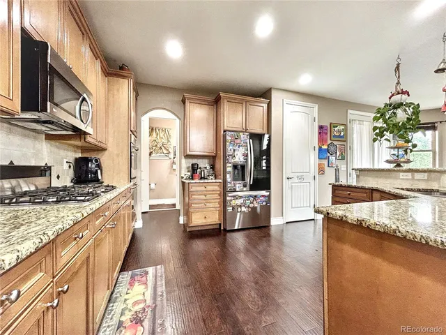 a large kitchen with stainless steel appliances granite countertop a lot of counter space and wooden floor